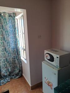 eine Mikrowelle auf einem Kühlschrank neben einem Fenster in der Unterkunft Cottage 1 in Nairobi