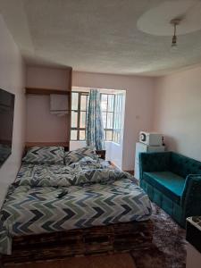 ein Schlafzimmer mit einem Bett und einem blauen Sofa in der Unterkunft Cottage 1 in Nairobi