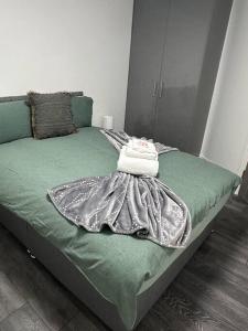 a bed with a green comforter and towels on it at 2Bed flat In Leicester ! in Leicester