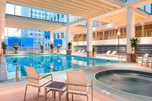 - une piscine dans un hôtel avec des chaises et un bâtiment dans l'établissement Delta Hotels by Marriott Winnipeg, à Winnipeg