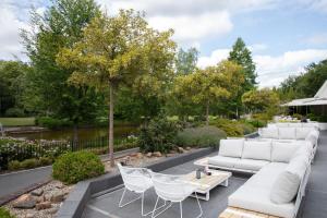 un patio con un divano bianco, sedie e alberi di Landgoed de Rosep a Oisterwijk