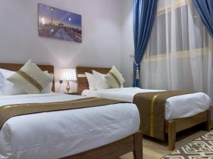 a bedroom with two beds with blue curtains at Landmark Hotel Suites in Tabuk