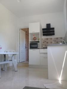 - une cuisine blanche avec une table et un four micro-ondes dans l'établissement petite maison à louer à la forét de corniche Bizerte, à Bizerte