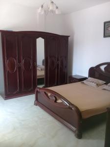1 dormitorio con 1 cama y un gran armario de madera en petite maison à louer à la forét de corniche Bizerte, en Bizerte