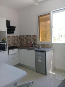 cocina con armarios blancos, fregadero y ventana en petite maison à louer à la forét de corniche Bizerte en Bizerte