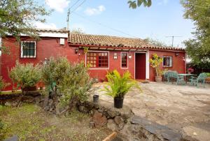 a red house with a patio in front of it at Casa Rural La Asomada in Vega de San Mateo