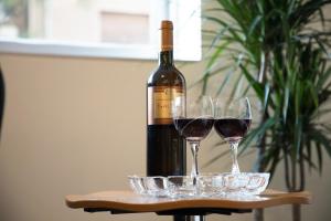 una botella de vino sentada en una mesa con dos copas en Diamerisma-Grafeio, en Pireo