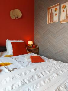 a bedroom with a white bed with a red wall at DE BLOEMENTUIN / A VIRÁGOSKERT in Tiszafüred