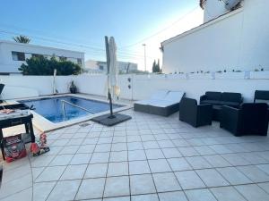a patio with an umbrella and a swimming pool at Charmante villa avec piscine dans les canaux in Empuriabrava
