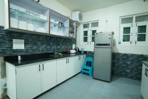 a kitchen with white cabinets and a refrigerator at Nature's Edge Nishat Srinagar in Srinagar
