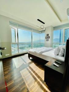 a bedroom with a large bed and large windows at Cherry On Top-Luxe Living in Islamabad's Skyline Elysium in Islamabad