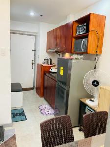a kitchen with a refrigerator and a table with chairs at JNL Victoria Sports Towers condo - GMA, Quezon city in Manila