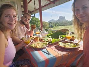 Un groupe de personnes assises à une table avec de la nourriture dans l'établissement Sigiriya Water Guest & View Point Restaurant, à Sigirîya