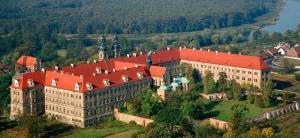 a large building with a red roof on a hill at Chata Opata in Lubiąż