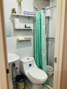 a bathroom with a toilet and a green shower curtain at JNL Victoria Sports Towers condo - GMA, Quezon city in Manila