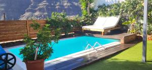 a swimming pool in a backyard with a chair next to it at Casa Agustín Pool 27 ºC in Fátaga