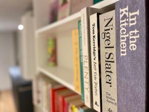 una fila di libri su uno scaffale in una biblioteca di Beautifully appointed one-bedroom cottage a Shepreth