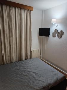 - une chambre avec un lit et une télévision murale dans l'établissement Guzet Neige 1400, à Ustou