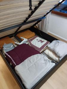 une boîte remplie de vêtements et d'oreillers sur un lit dans l'établissement Guzet Neige 1400, à Ustou