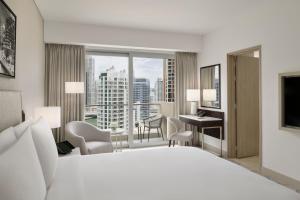 ドバイにあるJW Marriott Hotel Marinaのベッド、デスク、窓が備わるホテルルームです。