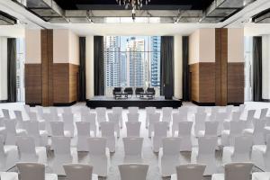 una sala de conferencias con sillas blancas y un escenario en JW Marriott Hotel Marina, en Dubái