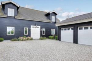 duży dom z dwoma białymi drzwiami garażowymi w obiekcie Eksklusivt hus på 250 m2 i naturskønne omgivelser w mieście Hørsholm