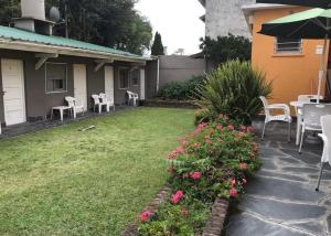 un patio trasero con mesa, sillas y flores en Hospedaje Acacia en Pinamar