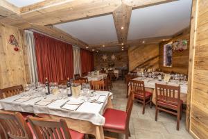 una sala da pranzo con tavoli, sedie e pareti in legno di HOTIDAY Chalet Sestriere Vialattea a Sestriere