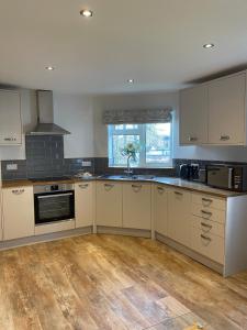 a large kitchen with white cabinets and a wooden floor at Stylish apartment, Taunton in Taunton