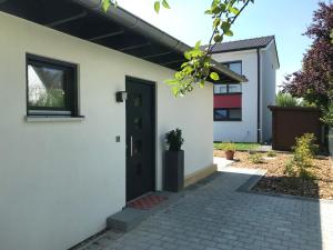 una casa bianca con una porta nera di Schöne 1,5 Zimmer Wohnung mit Aussenterrasse, Nice small 1,5 room flat with an outside terrace a Weichs