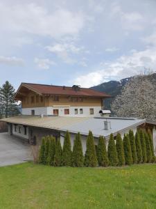 dom z rzędem drzew przed nim w obiekcie Pension Schlossberg w mieście Mittersill