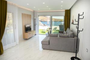 Sala de estar con sofá gris y TV en Beachfront Villa Kyma - Your own Private paradise, en Kalí Limenes