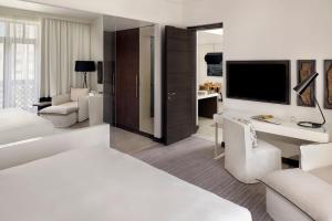 a white hotel room with a bed and a tv at Hotel Boulevard, Autograph Collection in Dubai