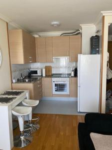 a kitchen with a white refrigerator and some bar stools at Recuncho Costeiro in Baiona