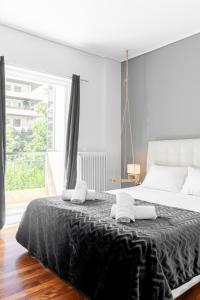 a white bedroom with a large bed with black sheets at Eclipse Marousi Ring in Athens