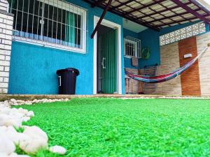 un edificio azul con un patio con césped verde en Suncoast House, en Cabo Frío