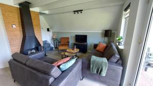 a living room with two couches and a fireplace at Luxe 6-persoons vakantiewoning Gramsbergs Huuske in Gramsbergen