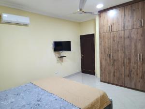 1 dormitorio con 1 cama, TV y armarios de madera en Jab Duplex, en Adentan