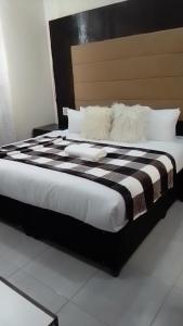 a large bed with black and white sheets and pillows at DBrite in Pretoria