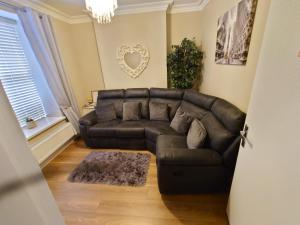 - un salon avec un canapé en cuir et une fenêtre dans l'établissement Helens House Derry City Centre Remarkable 3-Bed, à Derry Londonderry