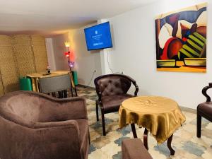 uma sala de estar com cadeiras, uma mesa e um quadro em Namaste hotel & restaurant em Libreville