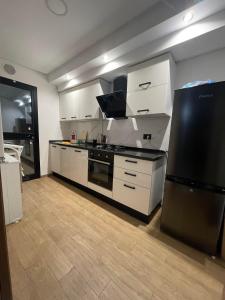 a kitchen with white cabinets and a black refrigerator at Un appartement S+1 agréable et spacieux ( terrasse) in Nabeul