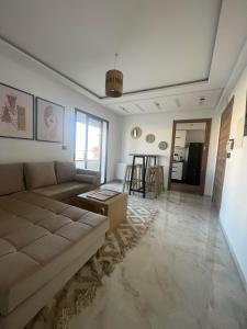 ein Wohnzimmer mit einem Sofa und einem Tisch in der Unterkunft Un appartement S+1 agréable et spacieux ( terrasse) in Nabeul