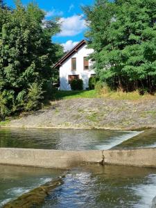 a white house on the shore of a river at Pustelnika Chatka nad Brennicą in Brenna