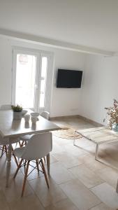 a white living room with a table and a tv at Appartement LE BOIS FLOTTE in Saintes-Maries-de-la-Mer