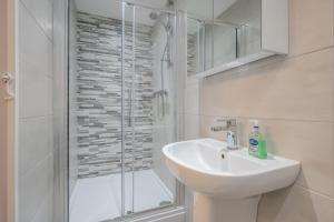 a white bathroom with a sink and a shower at Belfast City Centre - 3 bed, 3 bathroom & parking by StayByNumbers in Belfast