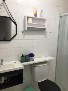 y baño con aseo, lavabo y espejo. en Apartamento Belas Artes Itanhaém en Itanhaém