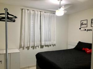 a bedroom with a black bed and a window at Apartamento Belas Artes Itanhaém in Itanhaém