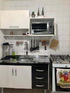 uma cozinha com um lavatório e um micro-ondas em Apartamento Belas Artes Itanhaém em Itanhaém