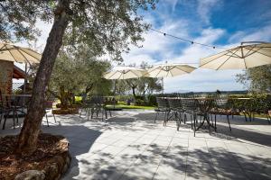 un patio con tavoli, sedie e ombrelloni di Agriturismo Podere Casato a Castelnuovo Berardenga